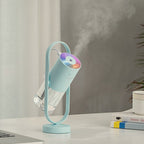Light Blue humidifier tilted in its stand, releasing mist on a white desk beside books