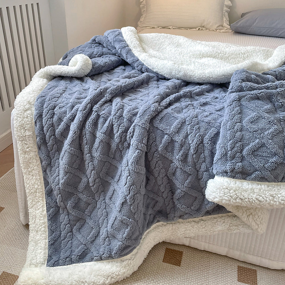 Dark Blue reversible sherpa throw blanket draped over a bed, white sherpa side folded back