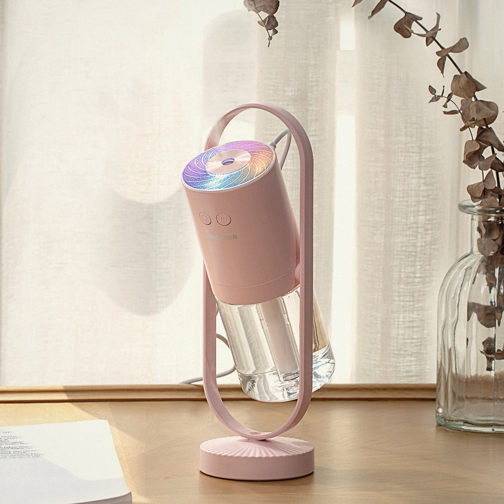 Pink humidifier with its light on, on a wooden table by a window