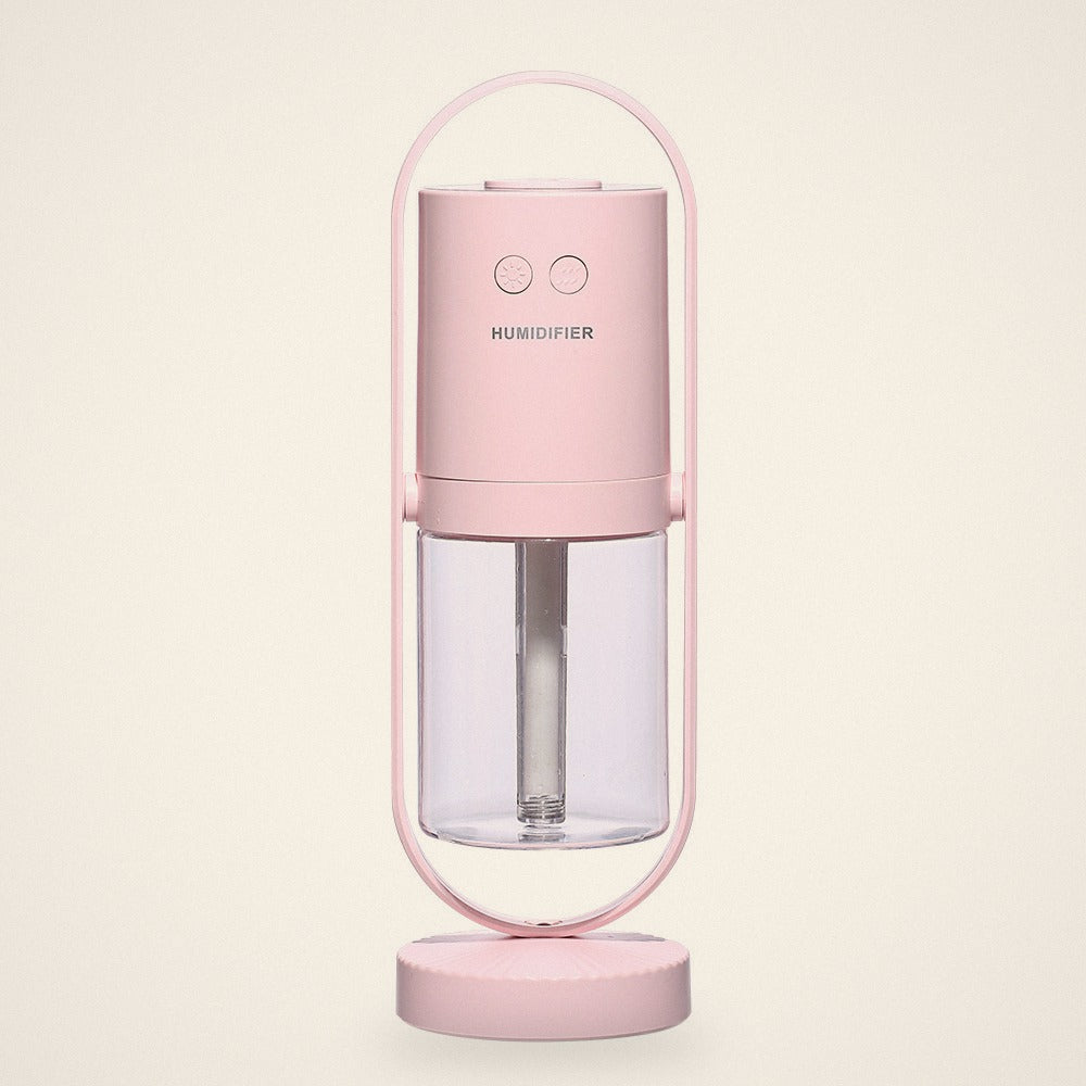 Pink mini USB humidifier in its oval stand with a clear water tank, front view