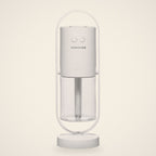 White mini USB humidifier in its oval stand with a clear water tank, front view