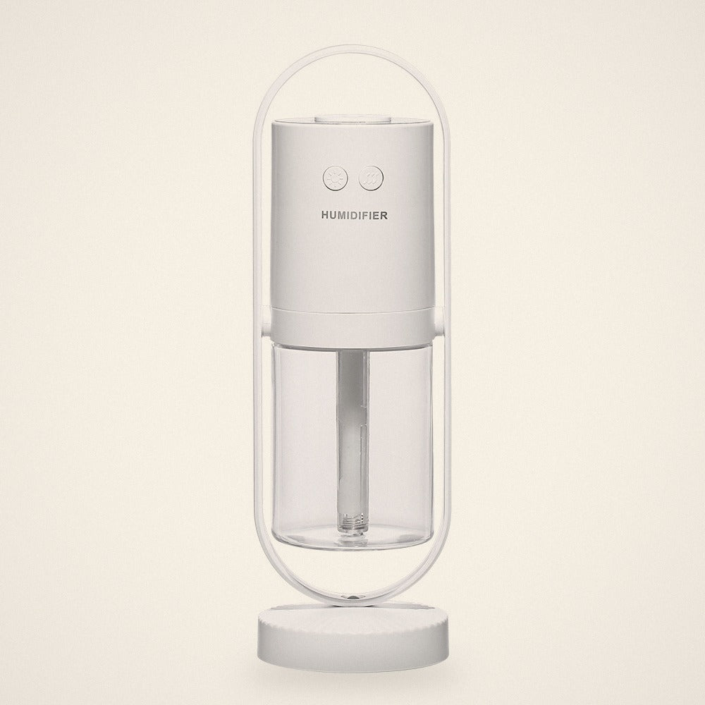 White mini USB humidifier in its oval stand with a clear water tank, front view