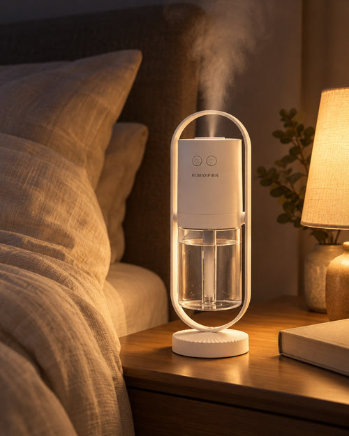 White mini USB humidifier releasing mist on a nightstand next to a lamp