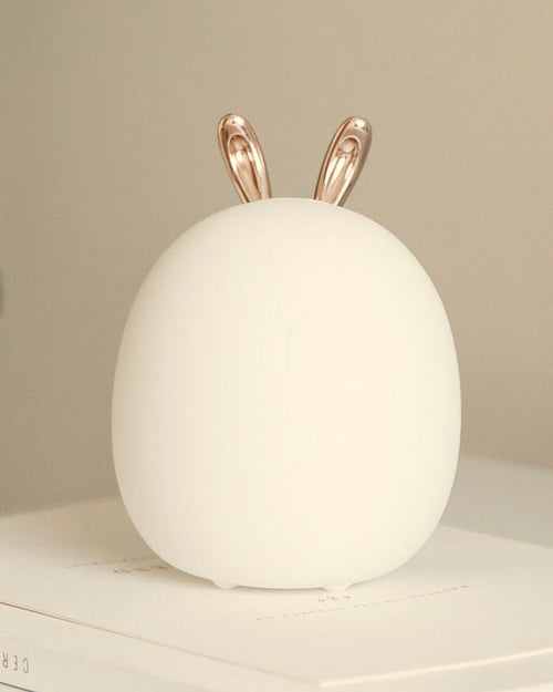 Mistglow bunny night light on a desk with books